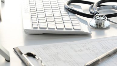 Escritorio de doctor con teclado, estetoscopio, y hoja de historial clínico. Portada del Diplomado en Administración de Salud